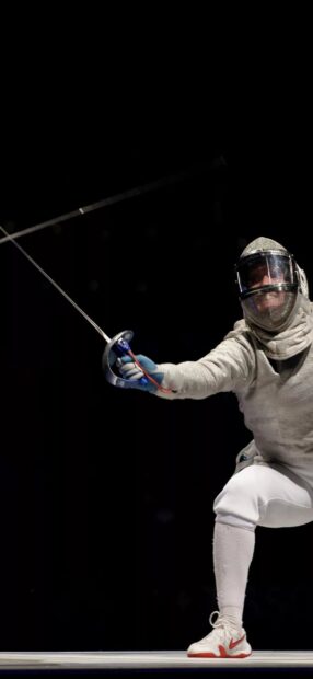 A fencer lunges forward holding a sword during a match in fencing, HD Mobile Wallpaper