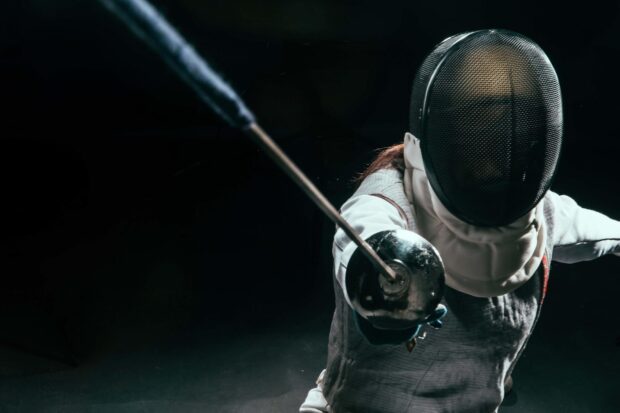 A fencer wearing protective gear is lunging forward with a foil during a match, HD Desktop Wallpaper