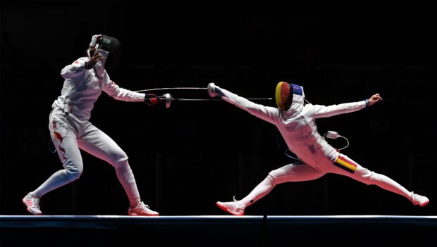 Two fencing athletes engage in an intense duel wearing protective gear and wielding foils, HD Desktop Wallpaper