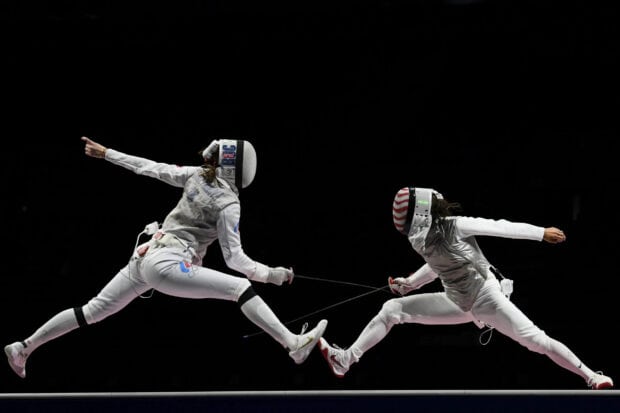 Two female fencers in full gear lunging during a fencing match, 2K Desktop Wallpaper