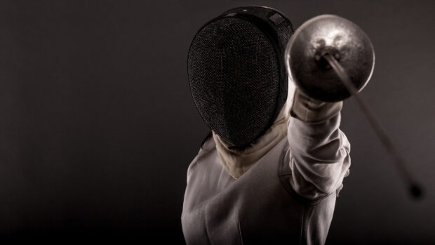 A fencing athlete wearing protective gear is lunging with a sword in hand, HD Desktop Wallpaper