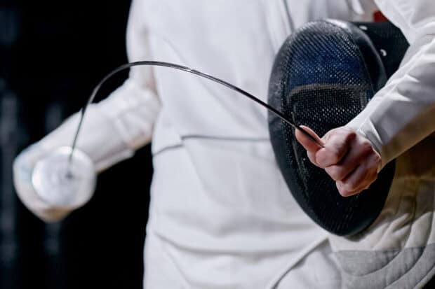 A close up of a fencing sword and mask held by an athlete during a match, 2K Desktop Wallpaper