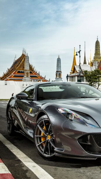 A sleek Ferrari 812 GTS parked by ornate temple structures under a blue sky, 4K Mobile Wallpaper
