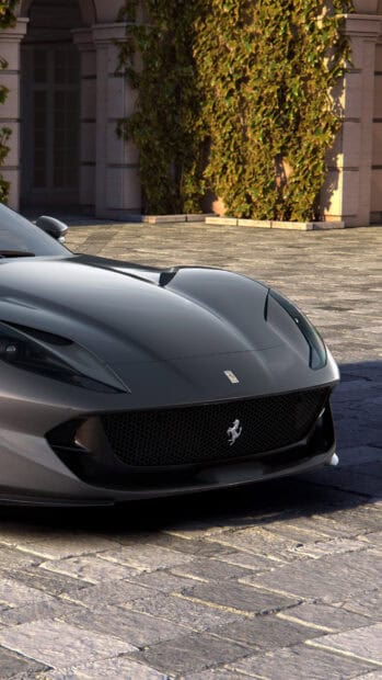 The Ferrari 812 Gts is parked on a stone pavement near greenery, 4K Phone Wallpaper