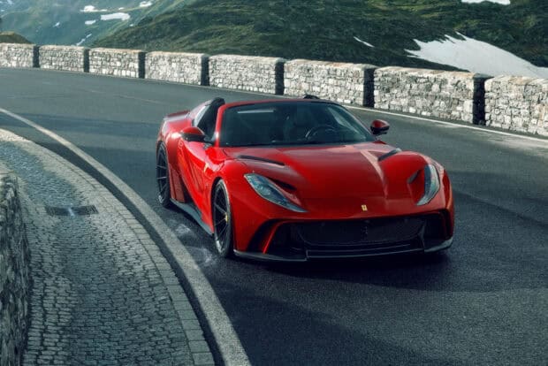 A red Ferrari 812 Gts is driving on a curved mountain road with stone barriers, 2K Desktop Wallpaper