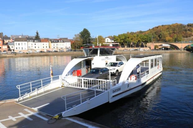 A ferry carrying multiple cars on a calm river near a small town and autumn trees, HD Desktop Wallpaper