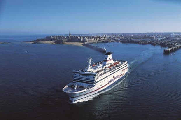 A large ferry sails near a historic coastal city with clear blue waters, 2K Desktop Wallpaper