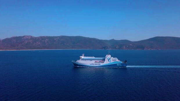 A ferry sails across deep blue water with mountains in the background, 4K Desktop Wallpaper