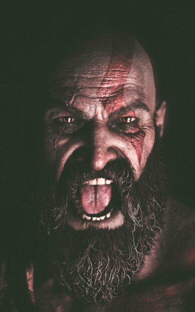 A close up of a fierce God of War character with war paint and an intense expression, HD Phone Wallpaper
