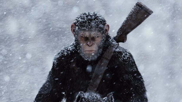 A fierce ape with snow on its fur stands determined in a snowy forest holding a weapon, 2K Desktop Wallpaper