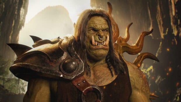 A fierce orc warrior with armor and tusks stands ready in a mystical forest, 4K Desktop Wallpaper