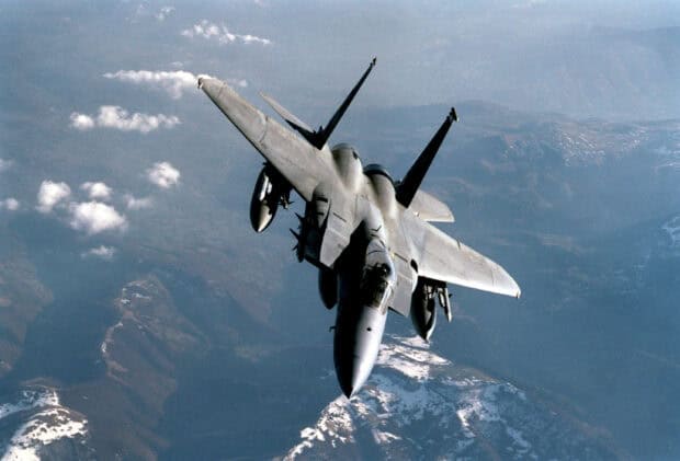 A jet fighter flying high above snowy mountains and clouds, 2K Desktop Wallpaper