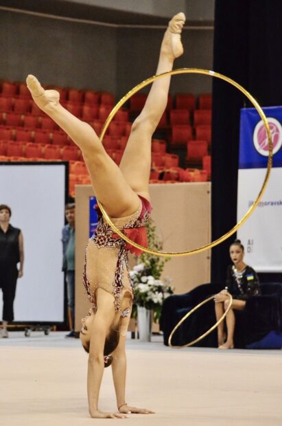 A gymnast performs an acrobatic gymnastics routine balancing a hoop during competition, HD Desktop Wallpaper