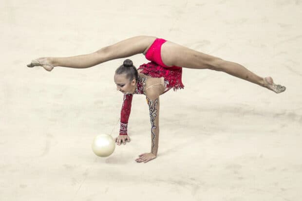 A gymnast performs a flexible routine with a ball on the floor, HD Desktop Wallpaper