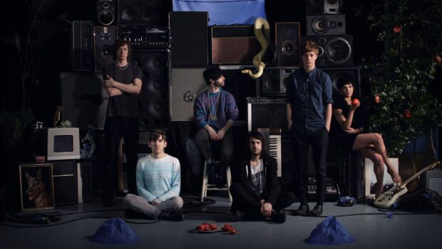 The Foals band members are posing with musical equipment and unique props in a dark room, HD Desktop Wallpaper