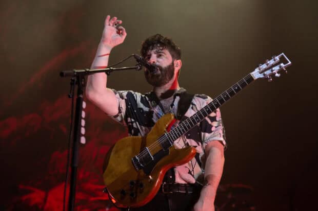 A Foals band member is singing and playing the guitar during a live concert, HD Desktop Wallpaper