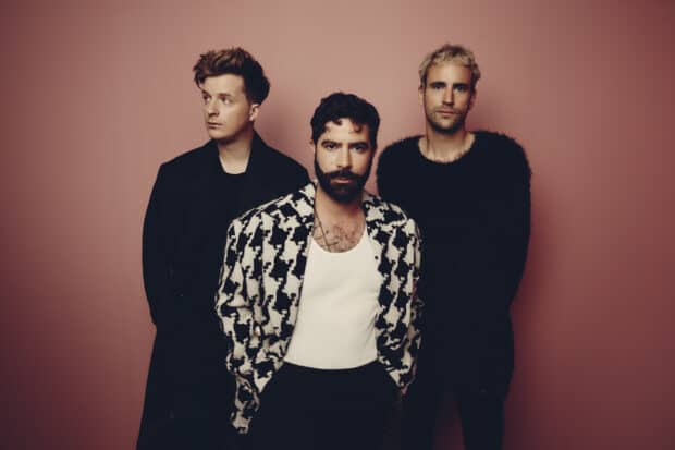 The Foals band members stand against a plain pink background in stylish outfits, HD Desktop Wallpaper