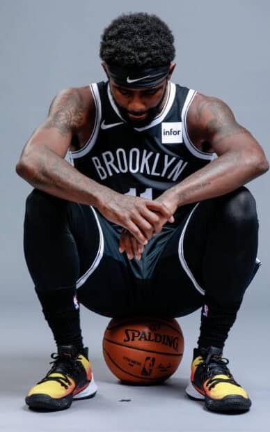 A basketball player wearing Brooklyn Nets jersey is deeply focused while sitting on a basketball, HD Mobile Wallpaper