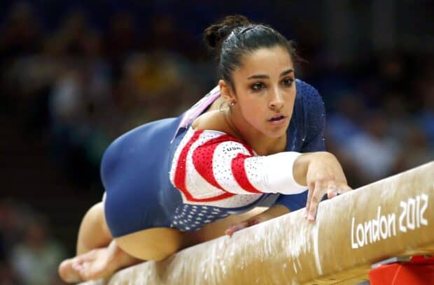 A gymnast is focused on her routine on the balance beam during a competition, HD Desktop Wallpaper