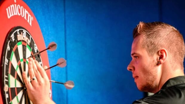 A focused player aims at a dartboard with darts stuck closely, HD Desktop Wallpaper