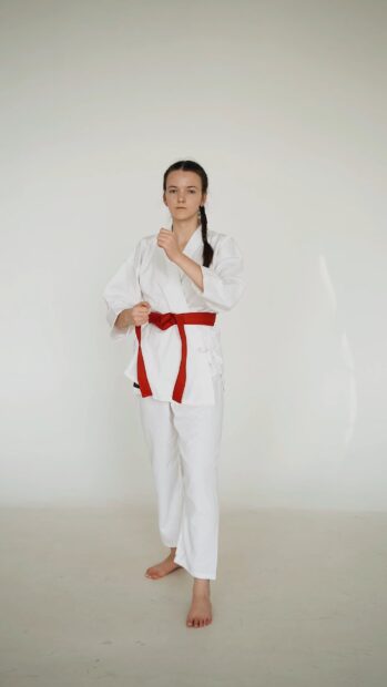 A young woman wearing a red belt is practicing karate moves in a white gi, HD Phone Wallpaper
