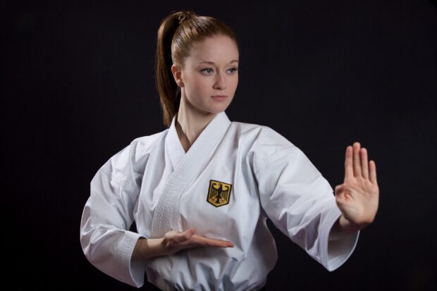 A female athlete demonstrates a focused karate stance wearing a traditional gi with an emblem, 2K Desktop Wallpaper
