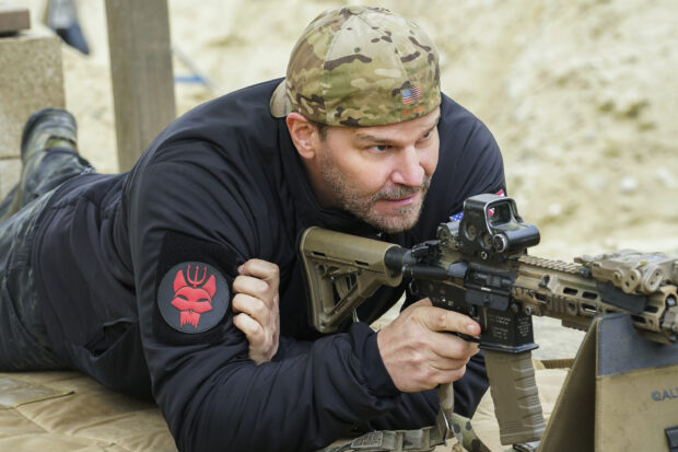 A man wearing camouflage aims a rifle in a Seal Team Tv Series setting, 2K Desktop Wallpaper