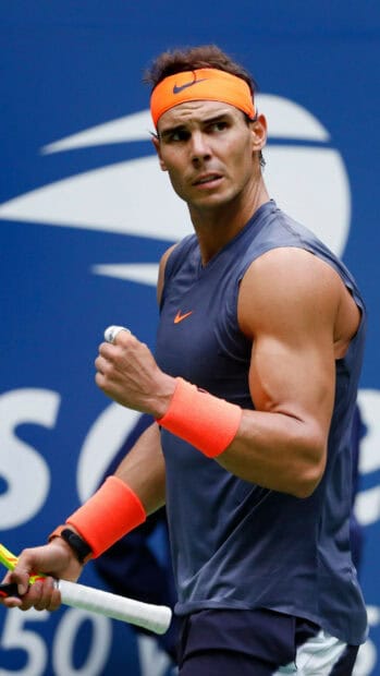 A tennis player wearing an orange headband and wristbands displays determination during a match, 2K Mobile Wallpaper