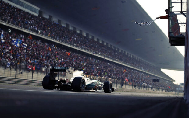 A race track featuring a Formula One car crossing the finish line with a crowd in the stands, HD Desktop Wallpaper