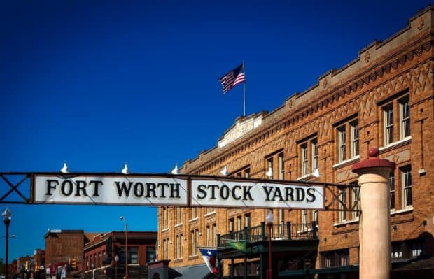 The Fort Worth Stock Yards sign stands prominently in front of historic brick buildings under a clear blue sky, Fort Worth Wallpapers, HD Desktop Wallpaper