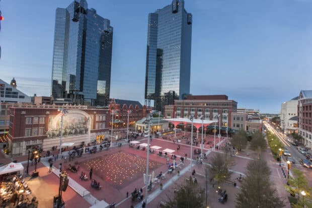 The Fort Worth city skyline shows modern buildings and a busy plaza during evening hours, HD Desktop Wallpaper