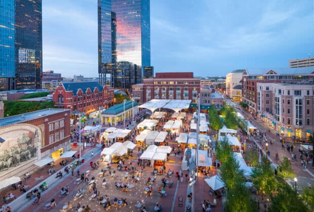 A vibrant view of Fort Worth with a lively market and tall buildings during evening, HD Desktop Wallpaper