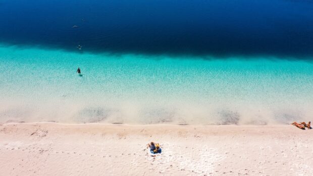 Two people relax on Fraser Island crystal clear beach near the water, HD Desktop Wallpaper
