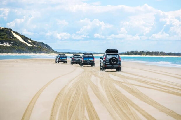 A convoy of vehicles driving on the sandy beach of Fraser Island, HD Desktop Wallpaper