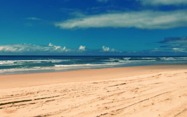 A wide sandy beach with waves at Fraser Island offers a peaceful view of nature, 2K Desktop Wallpaper