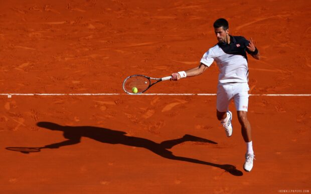 A tennis player is jumping to hit a forehand shot on the clay court at the French Open Roland Garros, 2K Desktop Wallpaper