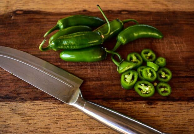 Fresh green jalapeno peppers are sliced next to a knife on a wooden cutting board, HD Desktop Wallpaper