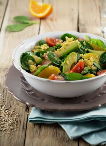 A bowl of fresh quinoa salad with avocado, spinach, and citrus slices on a wooden table, HD Mobile Wallpaper