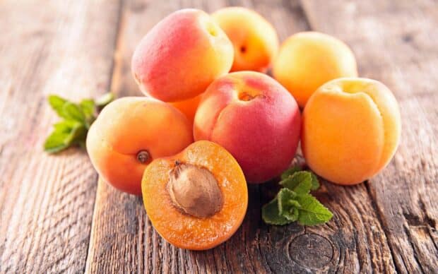Fresh ripe apricots are placed on a wooden surface with one cut open showing the seed in the center apricot wallpapers, HD Desktop Wallpaper
