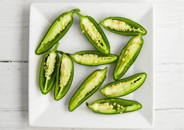 Fresh sliced jalapeno peppers arranged on a white plate showing seeds and green flesh, 2K Desktop Wallpaper