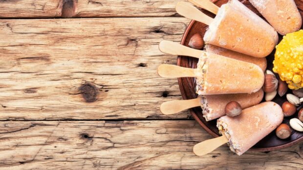 A close up view of frozen popsicles with nuts on a wooden plate placed on a rustic wooden surface, HD Desktop Wallpaper