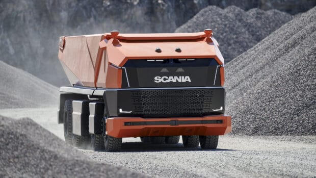 A futuristic Scania heavy truck is driving on a gravel surface surrounded by stones, 2K Desktop Wallpaper