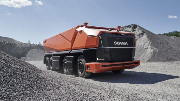 A futuristic Scania truck is parked on a gravel surface in a bright quarry with hills visible, 2K Desktop Wallpaper