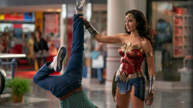 Gal Gadot Wonder Woman Wallpapers shows Wonder Woman holding a man by the leg in a busy mall, HD Desktop Wallpaper