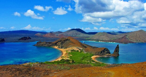 A stunning view of the Galapagos Islands with volcanic formations and blue ocean under a partly cloudy sky, 2K Desktop Wallpaper
