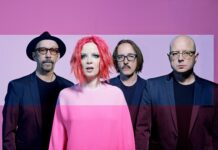 Garbage band members stand against a pink background wearing dark blazers and colorful outfits, HD Desktop Wallpaper