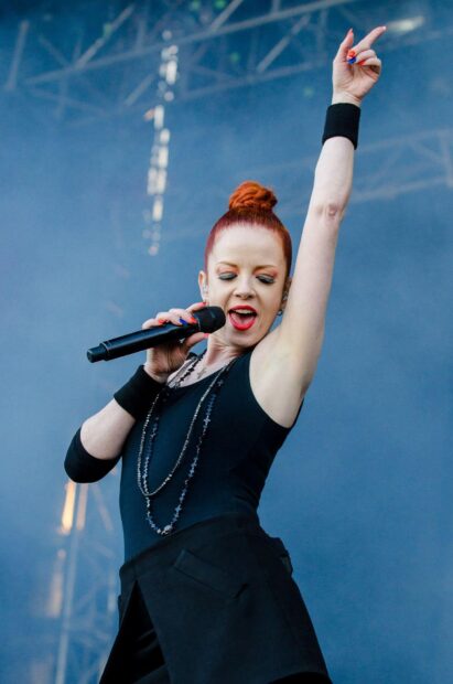 The Garbage Band lead singer energetically performs on stage with a microphone in hand, HD Mobile Wallpaper