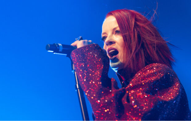 A female singer from Garbage Band is passionately performing on stage with a microphone, HD Desktop Wallpaper