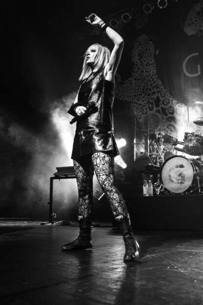 The Garbage Band lead singer raises her arm while performing live on stage, HD Mobile Wallpaper