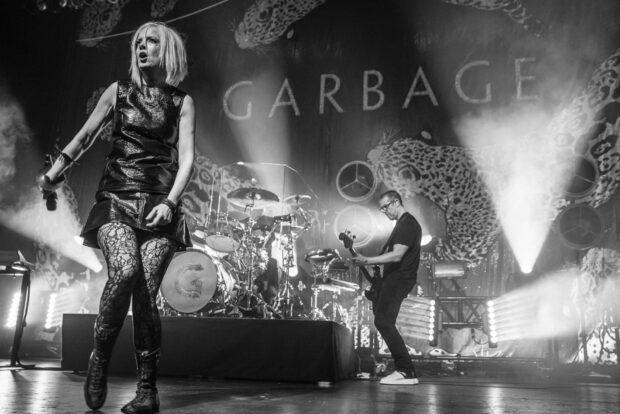 A black and white photo of Garbage Band performing on stage with instruments and lights, HD Desktop Wallpaper